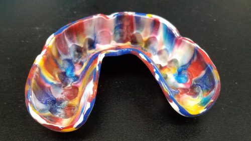 Multicolored marbled mouthguard on black background